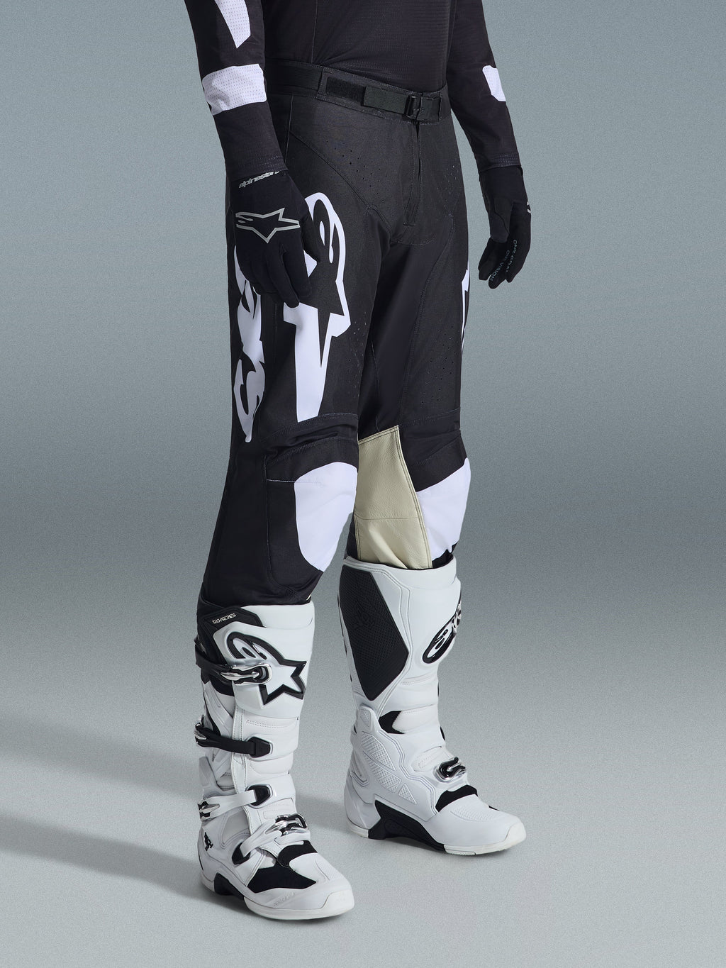 Alpinestars 2026 Racer Air Riway byxor, motocrossbyxor, svarta och vita, bärs med vita och svarta Tech Series-stövlar och svart långärmad tröja, med vita Alpinestars-logotyper, laserskurna perforeringar och beige innerpaneler i getskinn på knäna för terrängprestanda.
