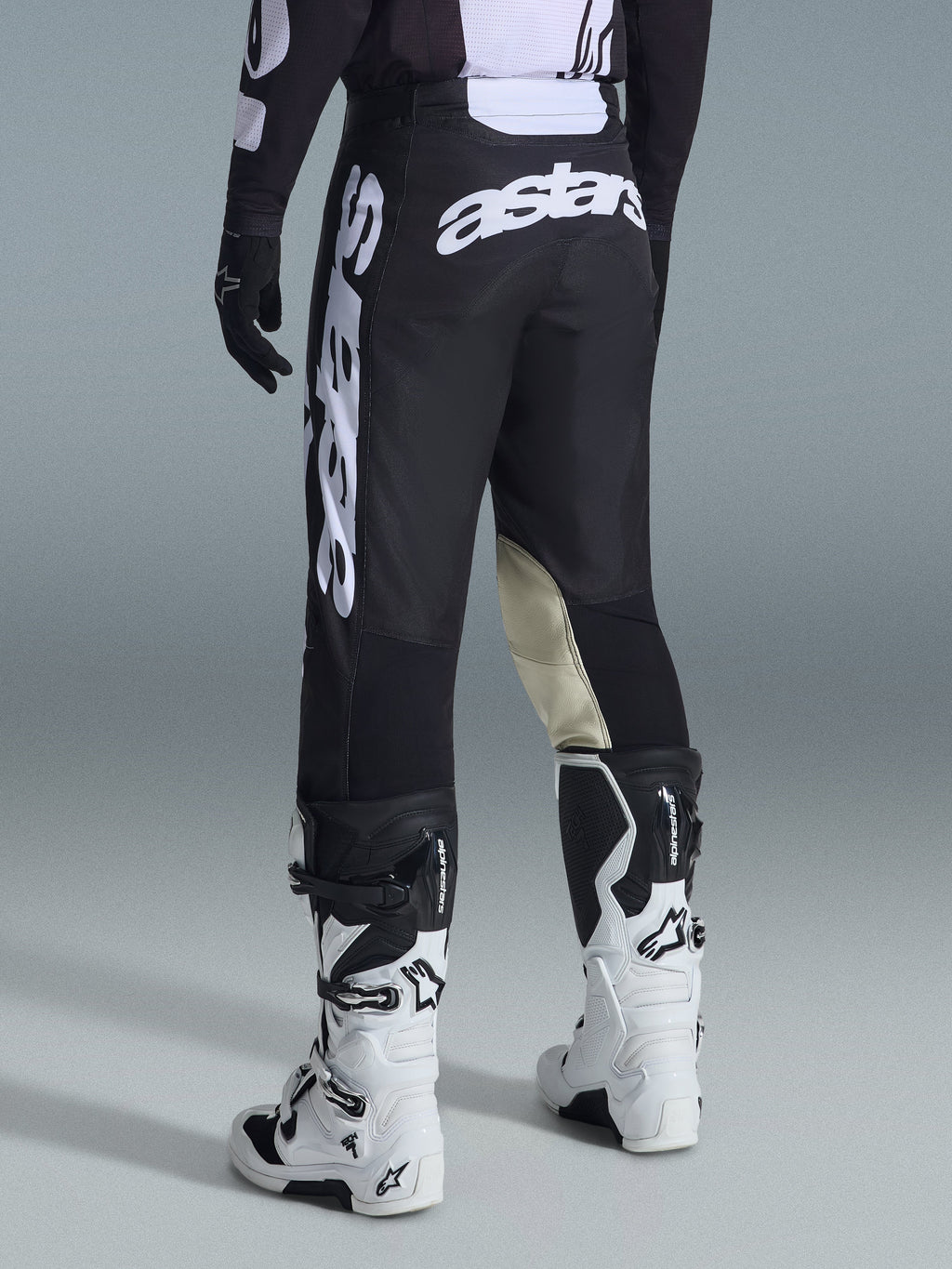 Alpinestars 2026 Racer Air Riway byxor, motocrossbyxor, svarta och vita, vy bakifrån med stor vit Astars-logotyp på sätet och benen, beige läderpaneler på knänas insida, bärs med vita och svarta Tech 7-stövlar, premium racingutrustning för terrängkörning