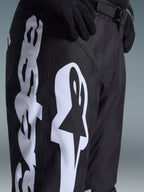 Alpinestars 2026 Racer Air Riway-byxor, motocrossbyxor, svarta och vita, närbild som visar stor vit Alpinestars-branding, laserskurna perforeringar för luftflöde och justerbart midjespänne, slitstarkt material för terrängkörning.