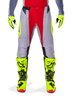 Alpinestars 2025 Techstar Melt-byxor, motocrossbyxor, ljusröd och grå, med en grå bas, röda mittpaneler och neongula sidodetaljer, laserskurna perforeringar för ventilation, bärs med neongula handskar och stövlar, högpresterande utrustning för terrängkörning