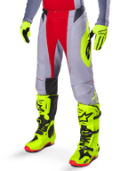 Alpinestars 2025 Techstar Melt Pants, Motocross Pants, Bright Red and Gray, featuring a prominent neon yellow logo, worn with matching neon yellow gloves and boots, athletic fit for motocross racing