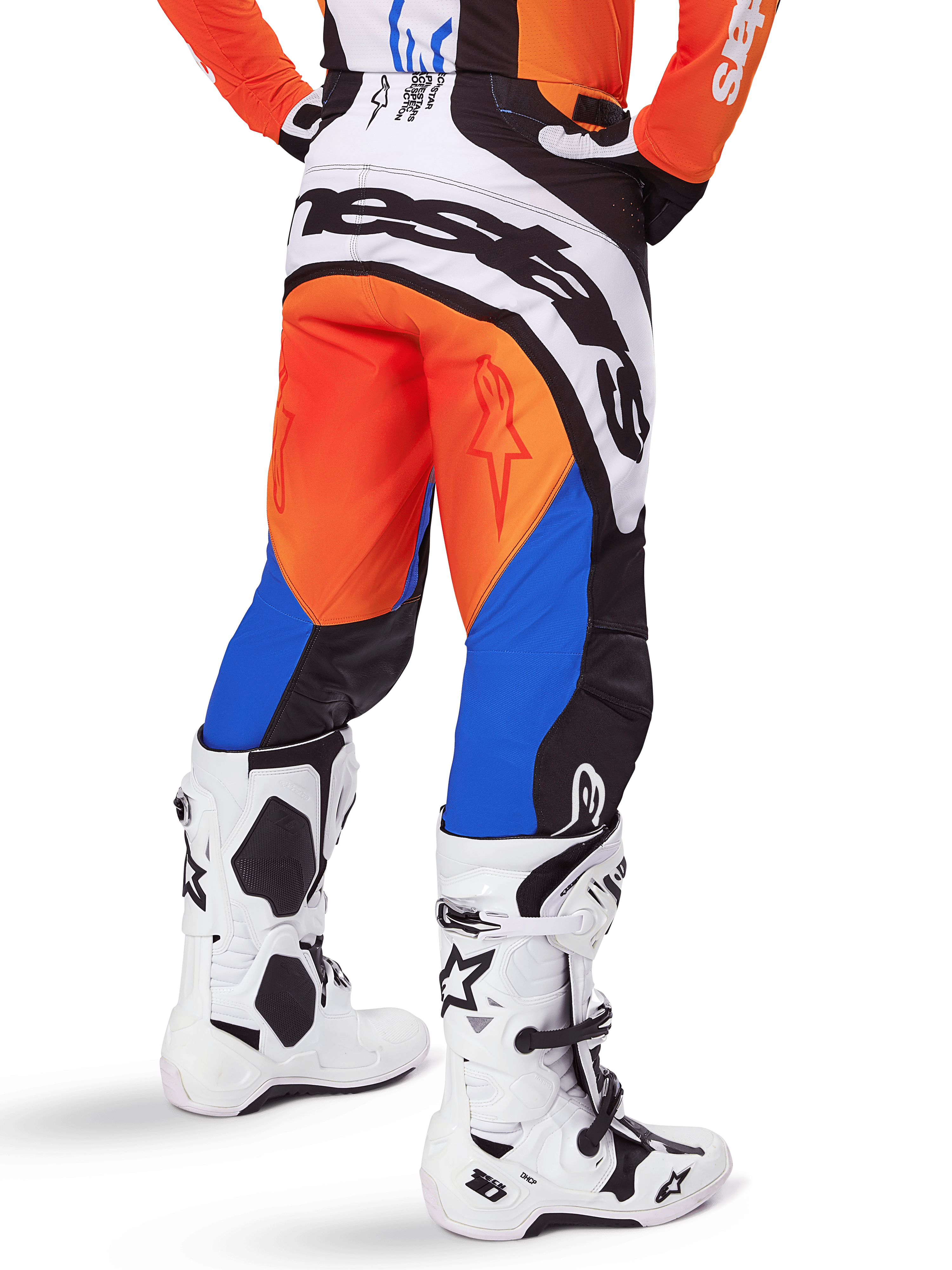 Alpinestars 2025 Techstar Melt byxor, motocrossbyxor, orange och blå, sedda bakifrån, med stor vit logotyp på sätet, bärs med matchande orange tröja och vita Tech 10-stövlar, hållbar racingutrustning för terrängkörning