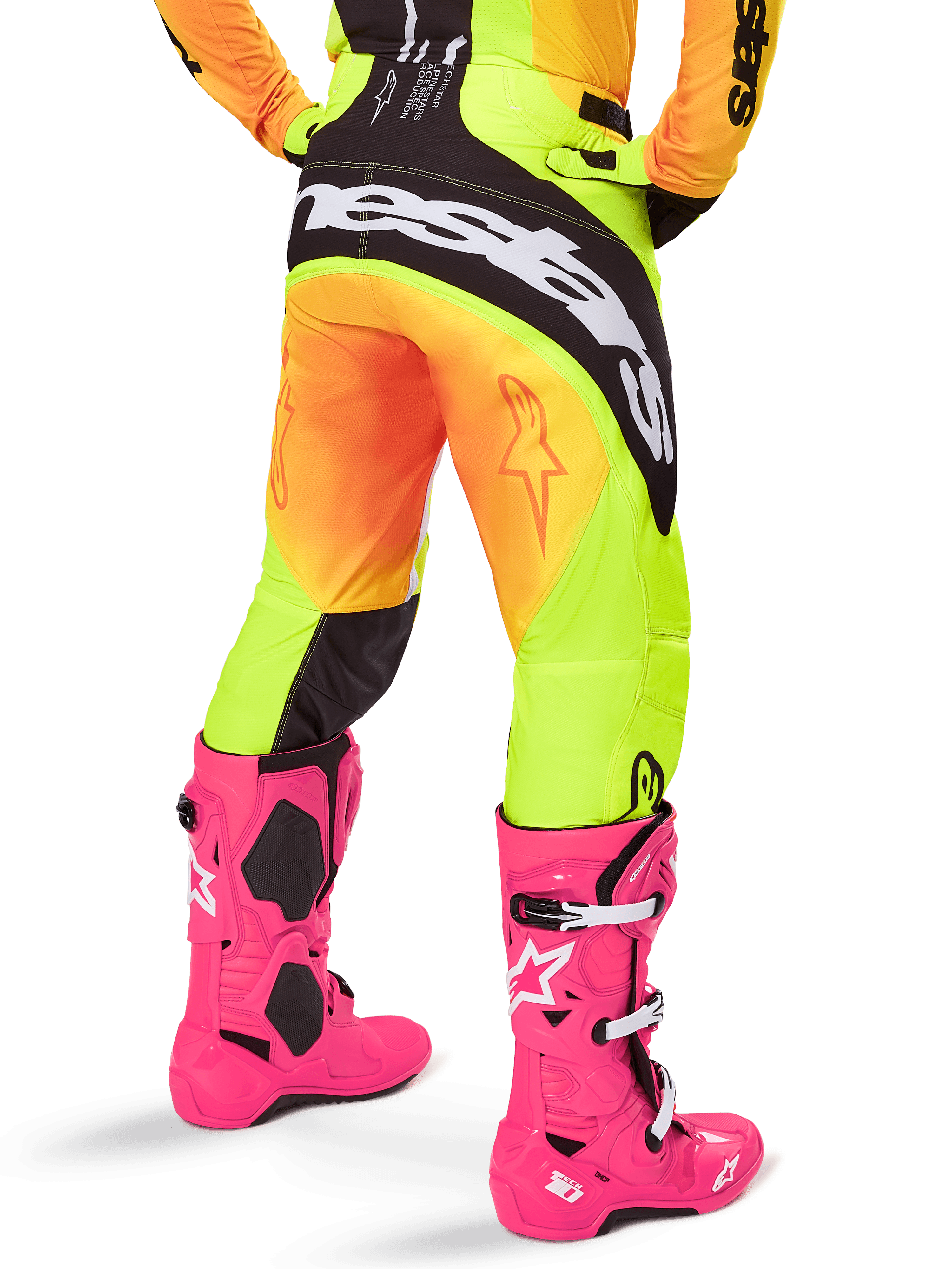 Rear view of a motocross rider wearing Alpinestars 2025 Techstar Melt Pants, Yellow and Orange gradient with black and white branding on the seat, paired with bright pink motocross boots, performance off-road gear.