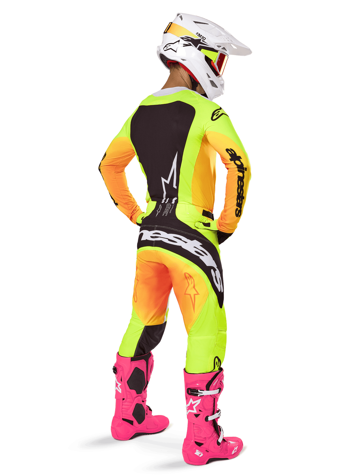 Motocrossförare sedd bakifrån iförd Alpinestars 2025 Techstar Melt-utrustningsset, gul och orange tonad tröja och byxor med svarta paneler, vit hjälm med röda goggles, starkt rosa stövlar, koordinerad racingoutfit för offroad-prestanda