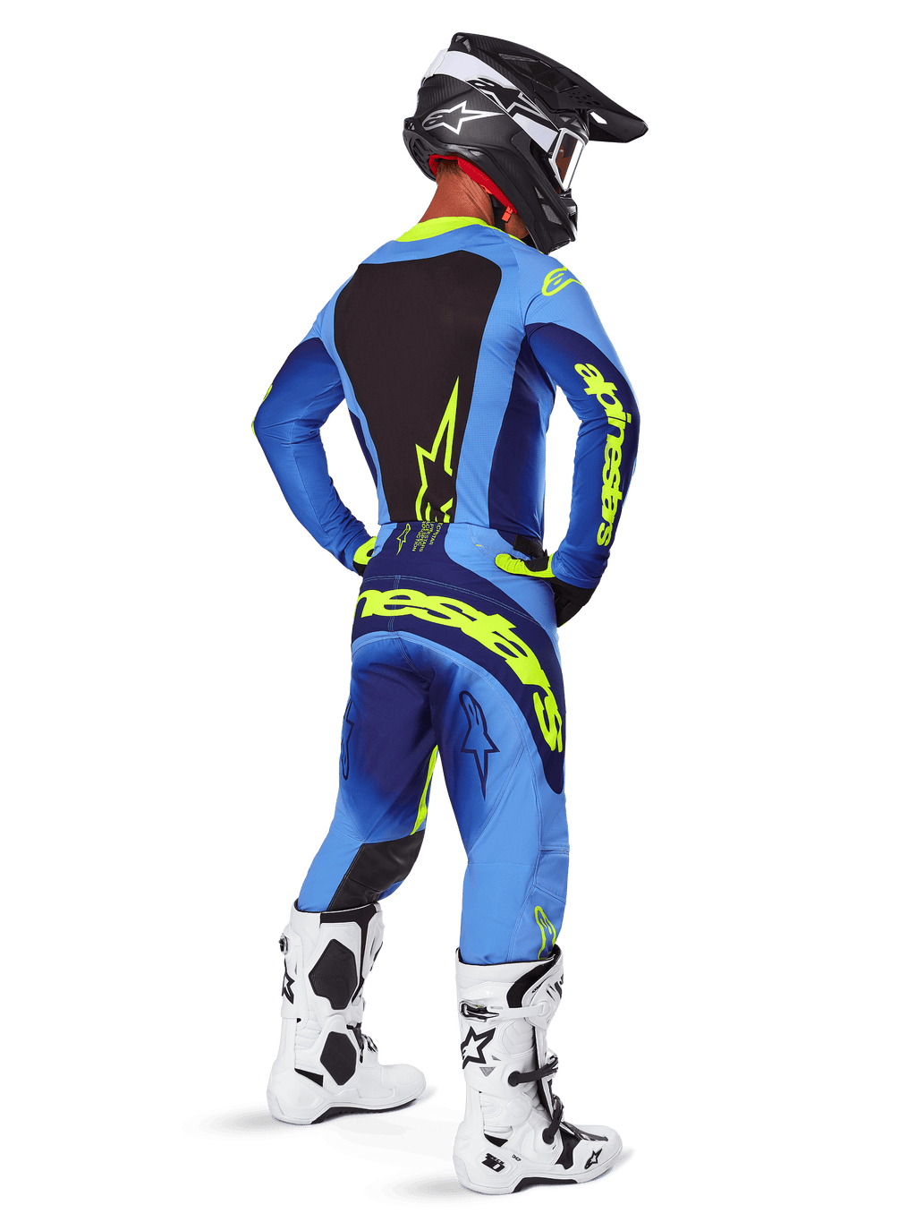 Alpinestars 2025 Techstar Melt byxor, motocrossutrustning, gul fluo och blå, vy bakifrån av förare som bär matchande blå tröja med stor gul logotyp, vita och svarta stövlar och svart hjälm, koordinerad racingoutfit för terrängprestanda