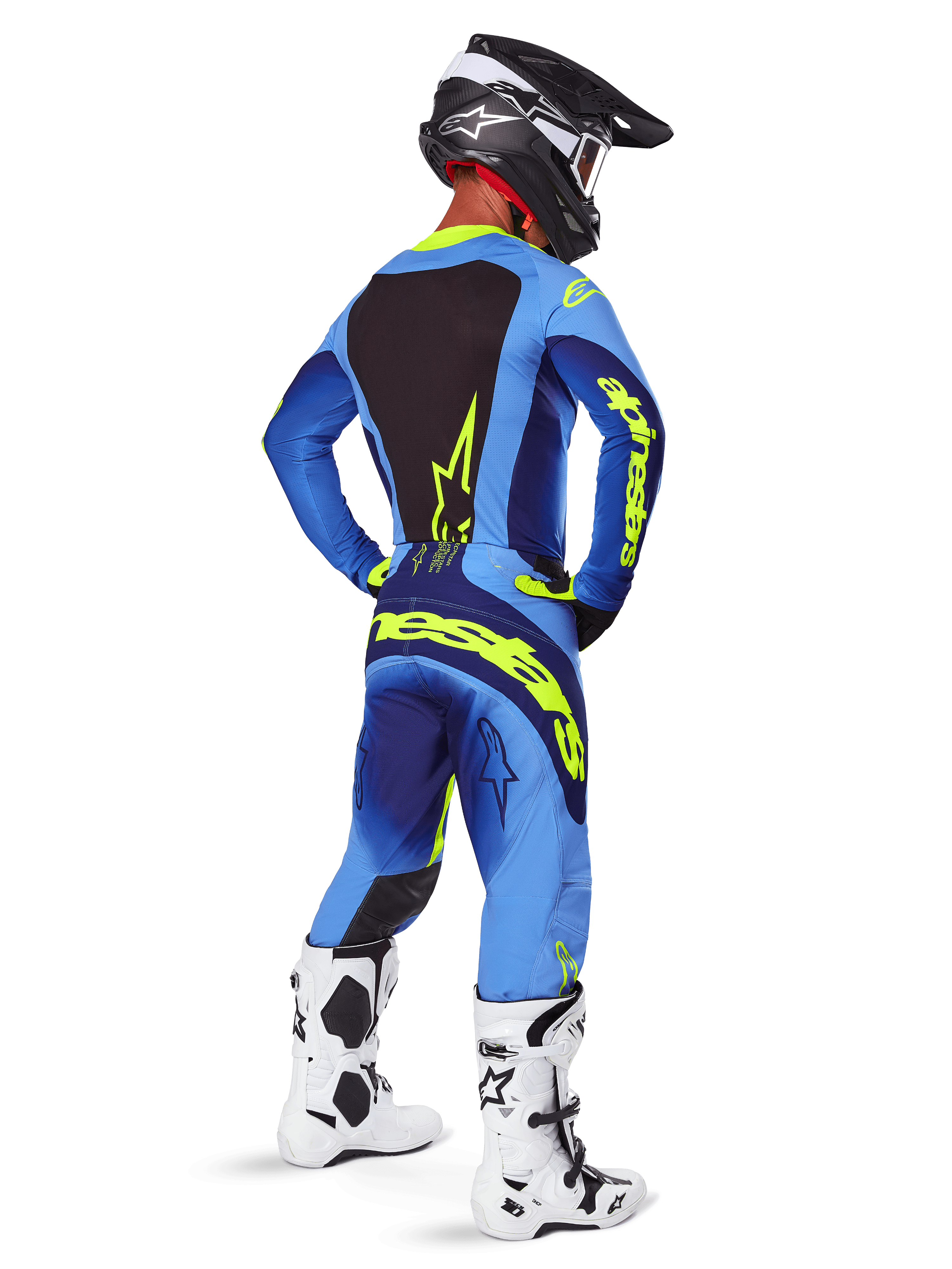 Alpinestars 2025 Techstar Melt byxor, motocrossutrustning, gul fluo och blå, vy bakifrån av förare som bär matchande blå tröja med stor gul logotyp, vita och svarta stövlar och svart hjälm, koordinerad racingoutfit för terrängprestanda