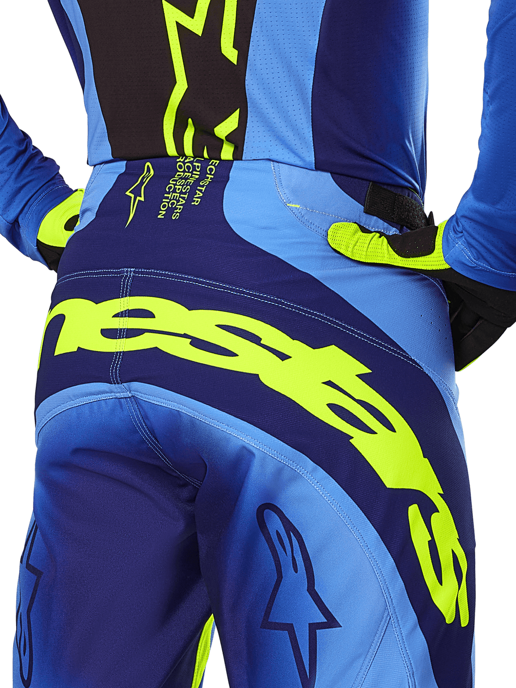Alpinestars 2025 Techstar Melt byxor, motocrossbyxor, gul fluo och blå, närbild bakifrån med tydlig gul Alpinestars-logotyp över sätet, bärs med matchande blå tröja och gul-fluo handskar, designade för högpresterande terrängkörning.