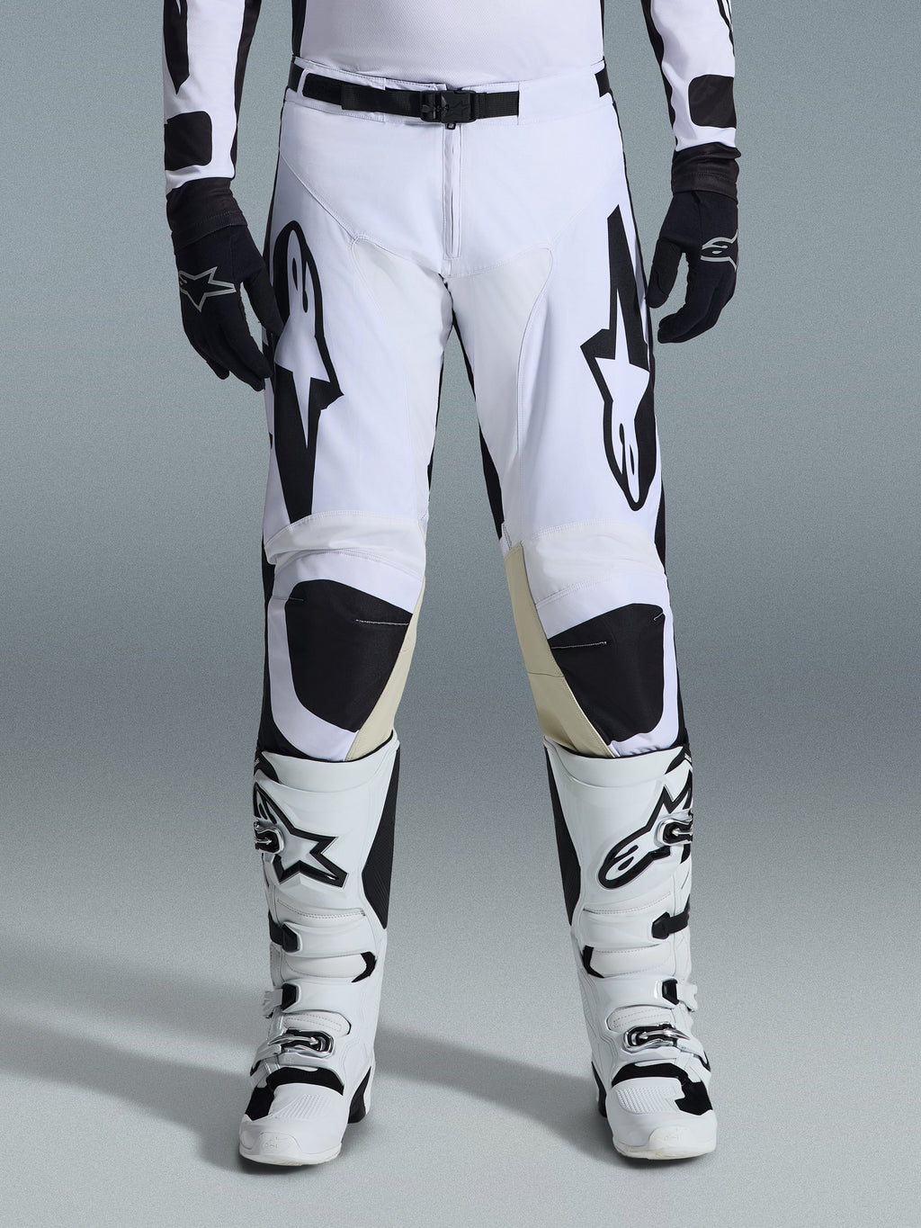 Alpinestars 2026 Racer Riway byxor, motocrossbyxor, vita och svarta, bärs med matchande vita och svarta motocross-stövlar och svarta handskar, med framträdande svart Alpinestars-logotyp på låren, teknisk design för offroad-prestanda.