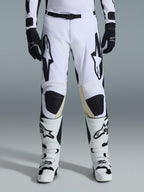 Alpinestars 2026 Racer Riway byxor, motocrossbyxor, vita och svarta, bärs med matchande vita och svarta motocross-stövlar och svarta handskar, med framträdande svart Alpinestars-logotyp på låren, teknisk design för offroad-prestanda.