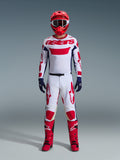 Motocrossförare i Alpinestars 2026 Racer Riway utrustningsset, vit tröja med röd "astars"-logotyp och blå sidopaneler, vita byxor med röd grafik, röd racinghjälm och stövlar, mörkblå handskar, komplett koordinerad motocrossutrustning