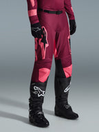 Alpinestars 2026 Racer Riway byxor, motocrossbyxor, Dark Red Coral, med stora rosa stjärnlogotyper och svarta paneler på insidan av knäna, bärs med svarta motocross-stövlar och svarta handskar, atletisk race-passform för terrängkörning