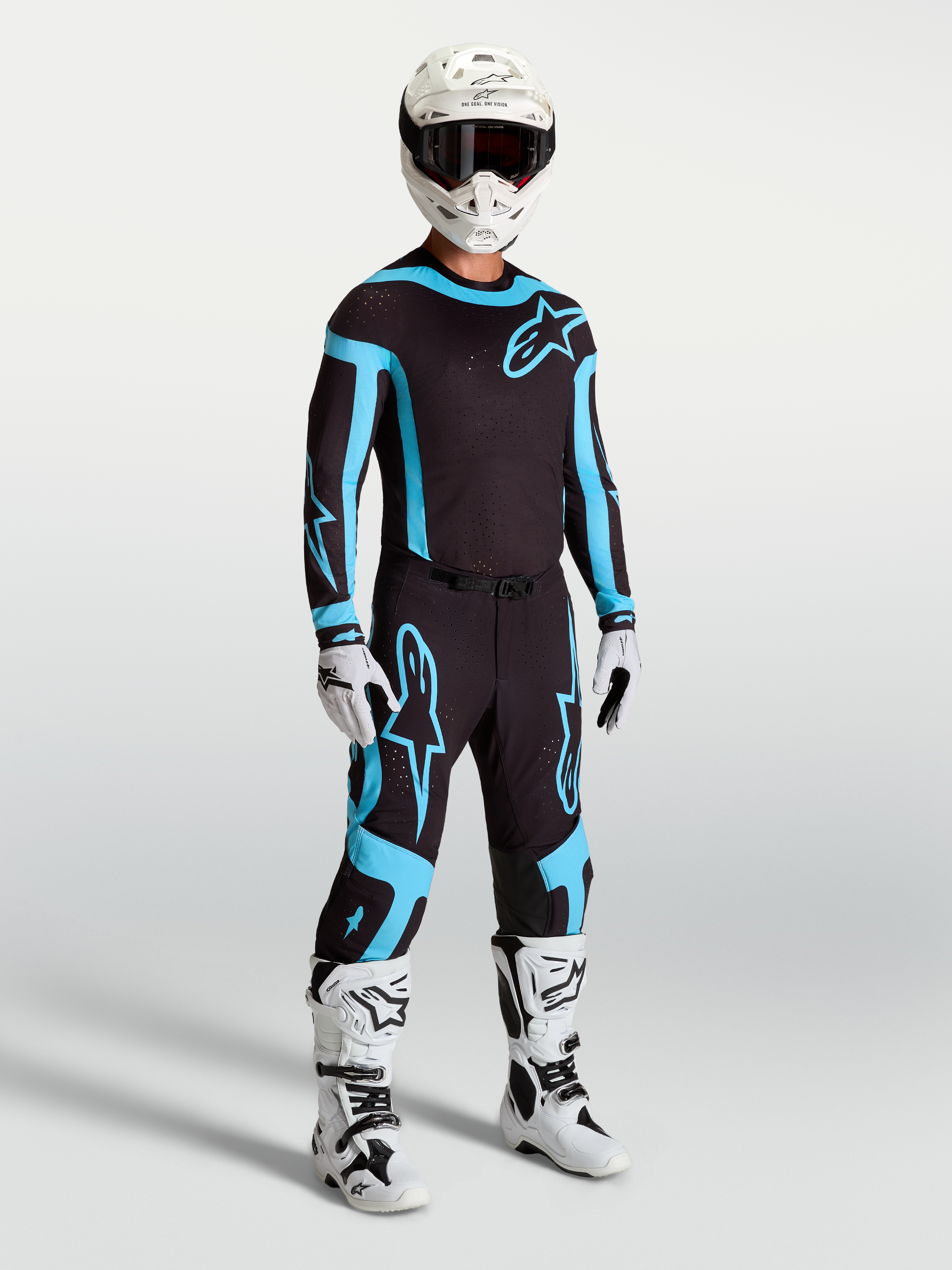 Alpinestars Supertech Vesta byxor, motocrossutrustning för herr, svarta och turkosa med vita stövlar och hjälm.