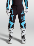 Alpinestars Supertech Vesta byxor, racingbyxor för motocross, svarta och turkosa med stora stjärngrafiker och knäpaneler i läder, bärs med matchande utrustning och vita stövlar.