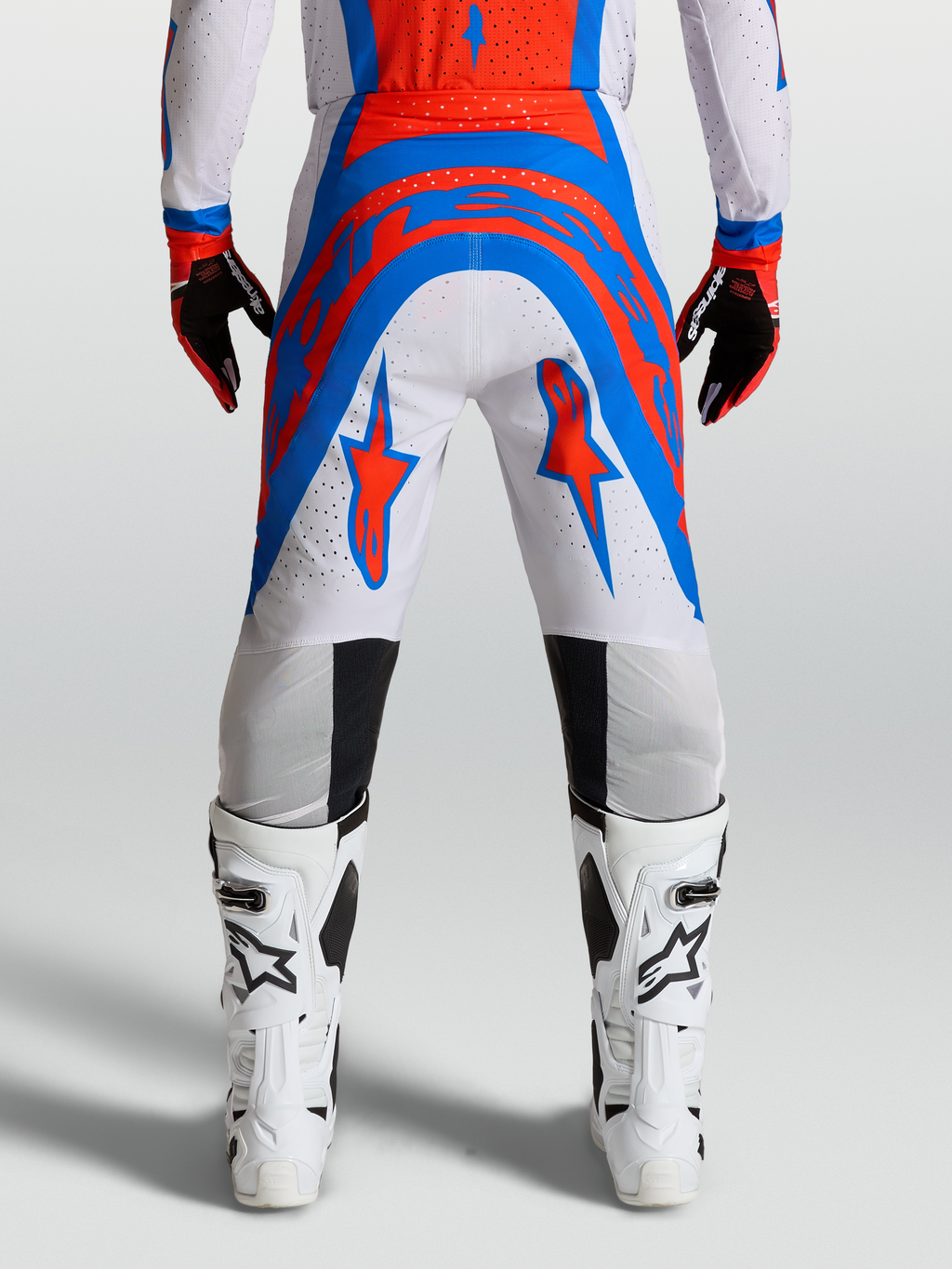 Alpinestars Supertech Vesta byxor, motocrossbyxor i lila och rött, atletisk passform bakifrån med vita stövlar.