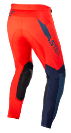 Alpinestars Supertech Blaze byxor, motocrossbyxor, klarröda och mörkblå, trekvartsvy bakifrån, med mörkblå ASTARS-logotyp på sidan, svarta förstärkta knäpaneler och atletisk passform för terrängprestanda.
