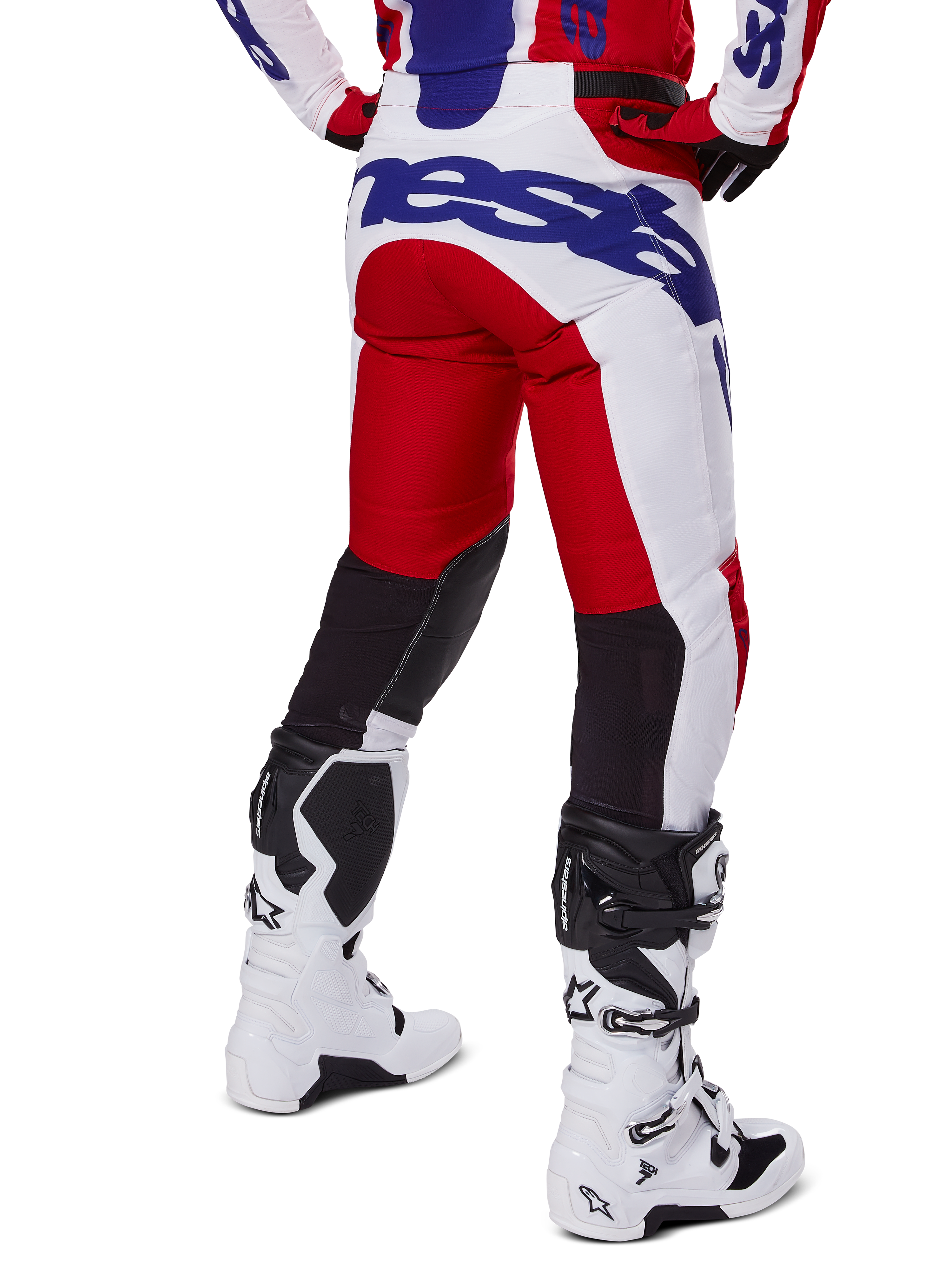 Alpinestars 2025 Racer Veil byxor, motocrossbyxor, klarröda och vita med blå logotyper, vy bakifrån som visar svarta stretchpaneler för ventilation på baksidan av benen, matchade med vita motocross-stövlar
