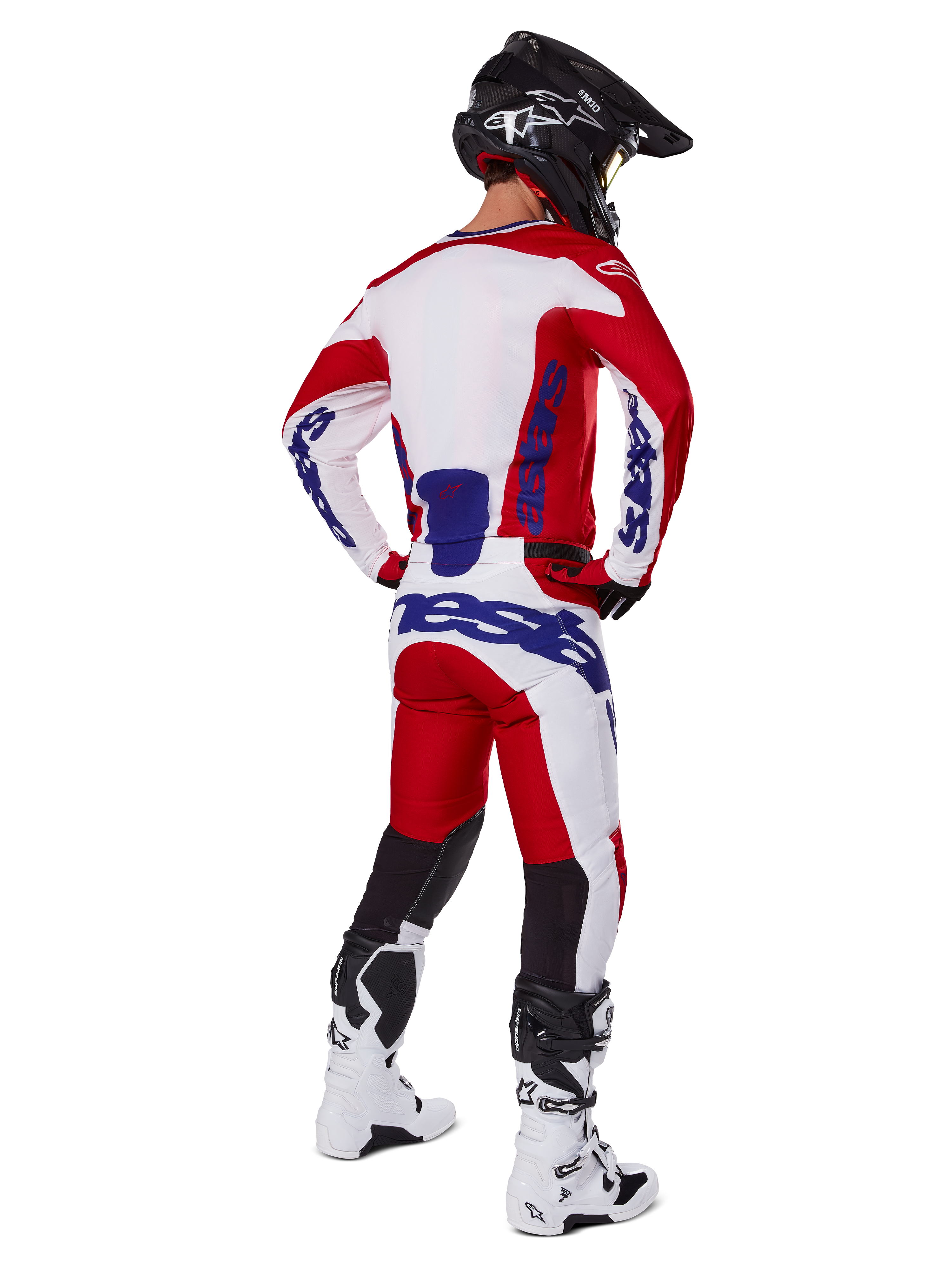 Alpinestars 2025 Racer Veil byxor, motocrossbyxor, klarröda och vita med blå detaljer, sedda bakifrån på en förare i full utrustning, framträdande Alpinestars-logotyp, ventilerande paneler på underbenen, matchande vita stövlar och svart hjälm.