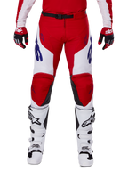 Alpinestars 2025 Racer Veil-byxor, motocrossbyxor, klarröda och vita, bärs med matchande röda handskar och vita stövlar, med blå logotyper på låren och ett svart midjebälte, ergonomisk sportskärning för prestandakörning