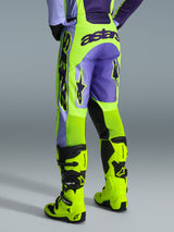Alpinestars 2026 Racer Portl-byxor, motocrossbyxor, lila och neongula, vy bakifrån med framträdande astars-logotyp och lila detaljer, bärs med matchande neongula motocross-stövlar, hållbart syntetmaterial för terrängkörning