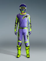 Alpinestars 2026 Racer Portl-byxor och matchande utrustningsset, motocrossförare i lila och gul fluo, med matchande tröja, hjälm, goggles och klar-gula stövlar, designade för prestanda vid terrängkörning.