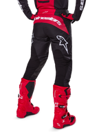 Alpinestars 2025 Fluid Haul utrustningsset, vy bakifrån, svarta och röda motocrossbyxor med stora vita logotyper, matchande tröja och klarröda Tech 7-stövlar, koordinerat racingkit för terrängkörning