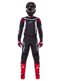 Alpinestars 2025 Fluid Haul utrustningsset, motocrossförare i komplett racingutrustning, svart tröja med röda axeldetaljer och vita logotyper, svarta byxor med vit stjärnlogotyp, klarröda stövlar, röda och svarta handskar, svart hjälm med vita goggles, koordinerad outfit för terrängkörning