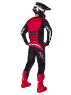 Motocrossförare som bär Alpinestars 2025 Fluid Haul-utrustningsset sedd bakifrån, röd och svart tröja med vit logotyp, matchande svarta byxor med röda detaljer, klarröda stövlar och svart hjälm med vita goggles, komplett koordinerad outfit för terrängkörning
