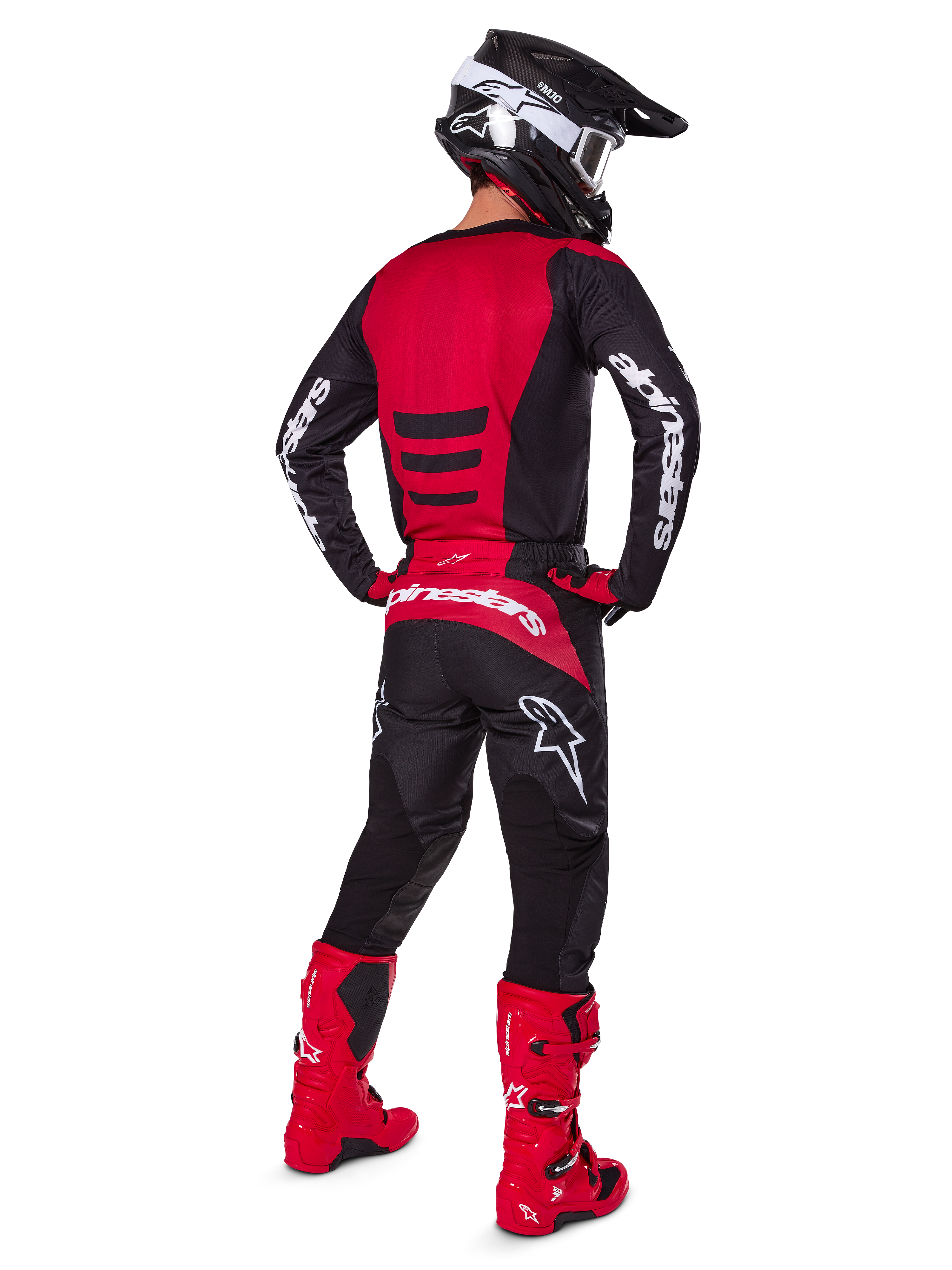 Motocrossförare som bär Alpinestars 2025 Fluid Haul-utrustningsset sedd bakifrån, röd och svart tröja med vit logotyp, matchande svarta byxor med röda detaljer, klarröda stövlar och svart hjälm med vita goggles, komplett koordinerad outfit för terrängkörning