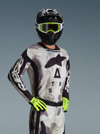 Alpinestars 2026 Racer Lahnd tröja, motocrosströja, Sand Camo med grått och svart mönster, stor Astars-logotyp på bröstet, bärs med svart hjälm, neongula goggles och handskar, prestandautrustning för offroad-racing