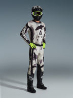 Motocrossförare i komplett Alpinestars racingutrustning, 2026 Racer Lahnd Byxor i Sand Camo, matchande camotröja med tydlig logotyp, svart hjälm med neongula goggles, neongröna handskar och svarta stövlar, professionell utrustning för terrängkörning