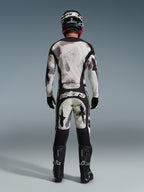Motocrossförare sedd bakifrån bärande 2026 Racer Lahnd Jersey och matchande byxor i Sand Camo, med ett krämvitt och grått abstrakt mönster med svarta paneler, 'astars'-logotyp på byxorna, matchat med svarta Alpinestars-stövlar och en svart hjälm för en komplett offroad-racinglook.