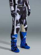 Alpinestars 2026 Racer Lahnd-byxor, motocrossbyxor, grått och svart Iron Camo-mönster, bärs med klarblå racingstövlar och matchande handskar, vita paneler och innerknän i getläder, prestandafokuserad utrustning för terrängkörning