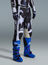 Alpinestars 2026 Racer Lahnd Pants, Motocross Pants, Iron Camo gray and black pattern, worn with bright blue racing boots and matching gloves, featuring white panels and goat leather inner knees, performance-driven off-road gear