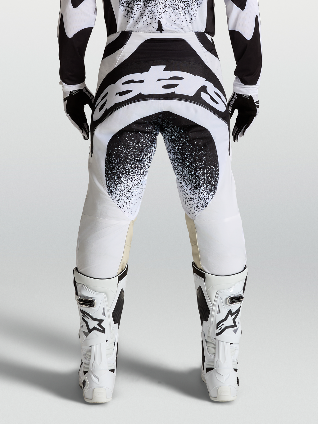 Alpinestars Techstar Swan byxor, motocrossbyxor sedda bakifrån, svarta och vita med stor logotypgrafik och Babel-knäkonstruktion