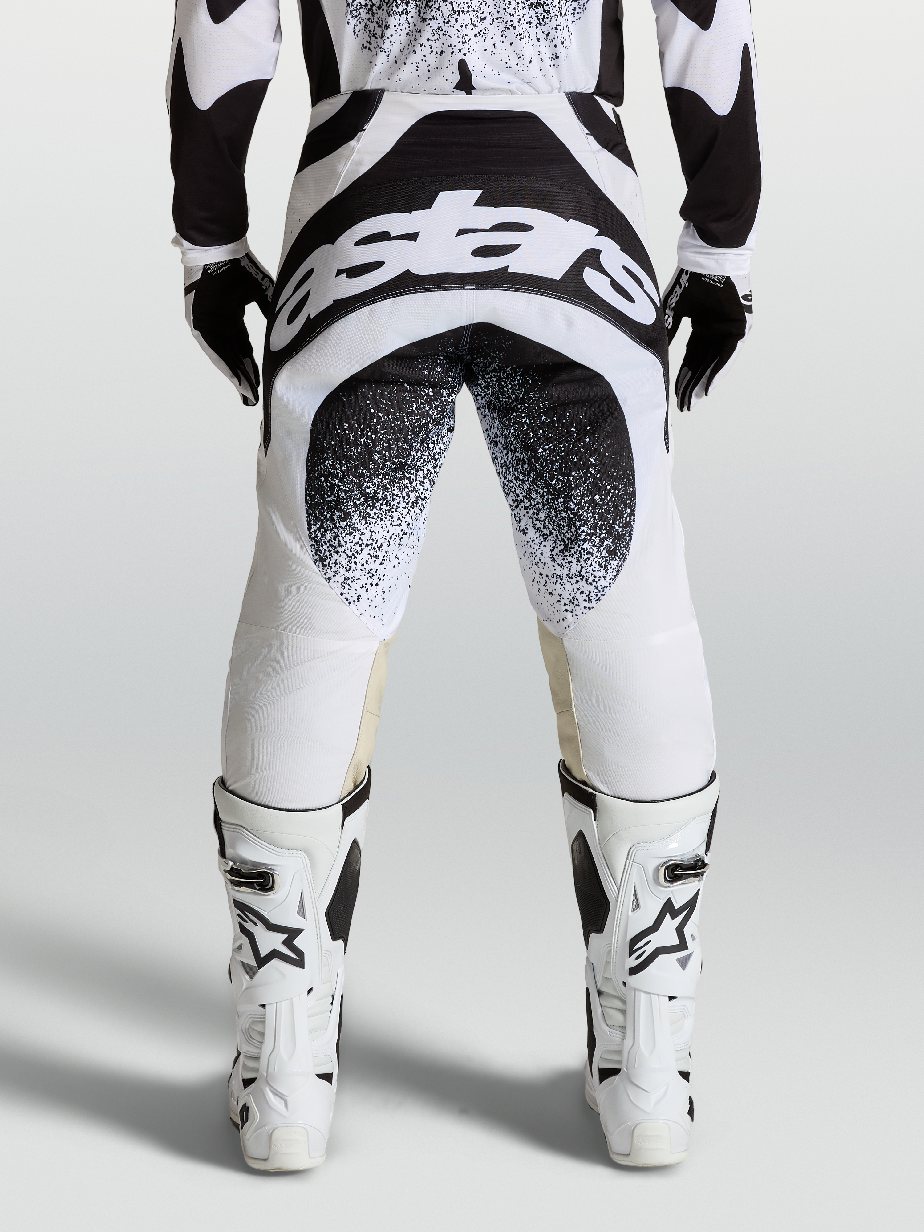 Alpinestars Techstar Swan byxor, motocrossbyxor sedda bakifrån, svarta och vita med stor logotypgrafik och Babel-knäkonstruktion
