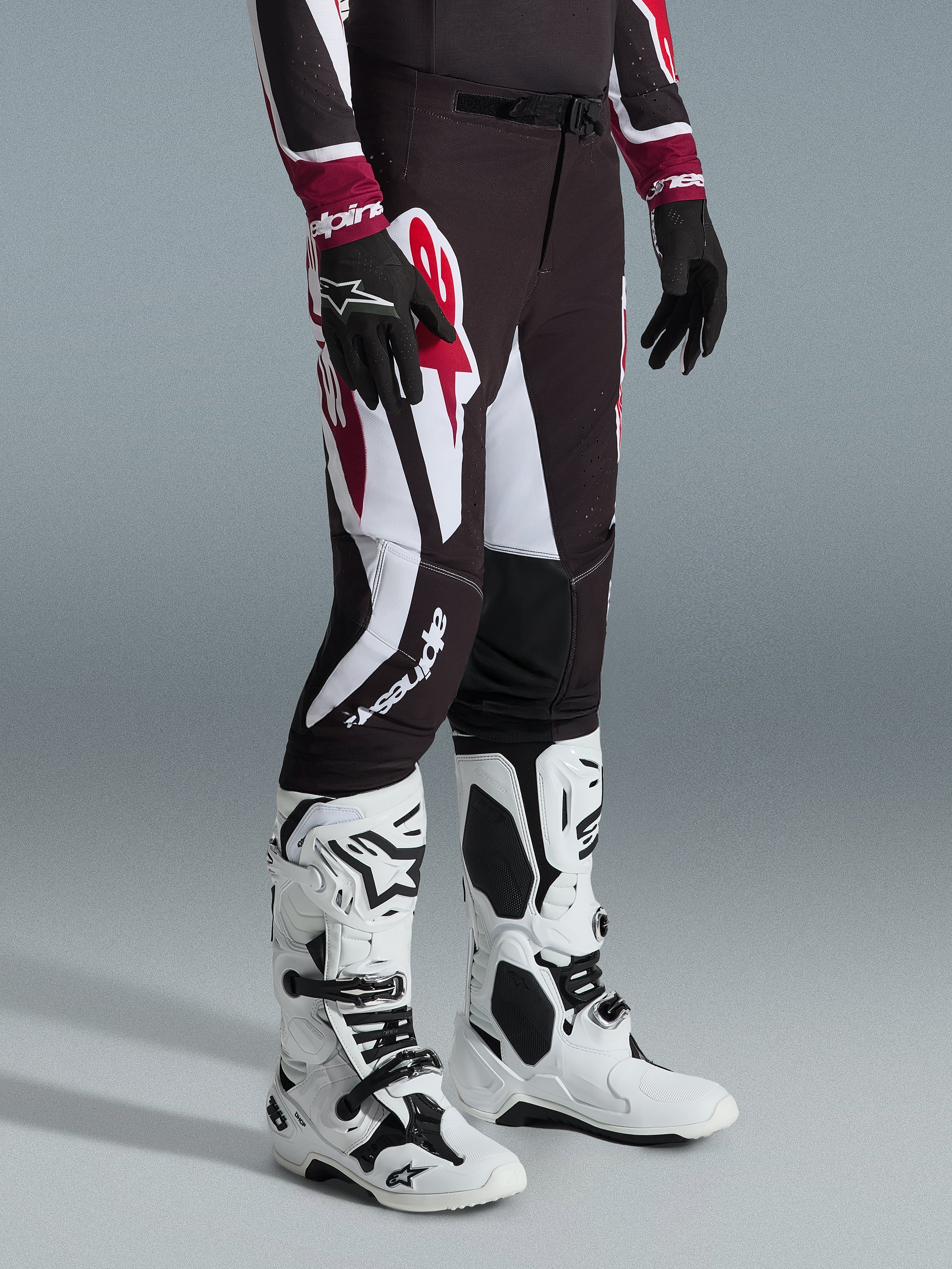 Alpinestars 2026 Supertech AFD Vista Pants, Motocross Pants, Black Red and White, featuring bold graphic patterns and branding, worn with white and black off-road boots and black gloves, professional athletic fit.