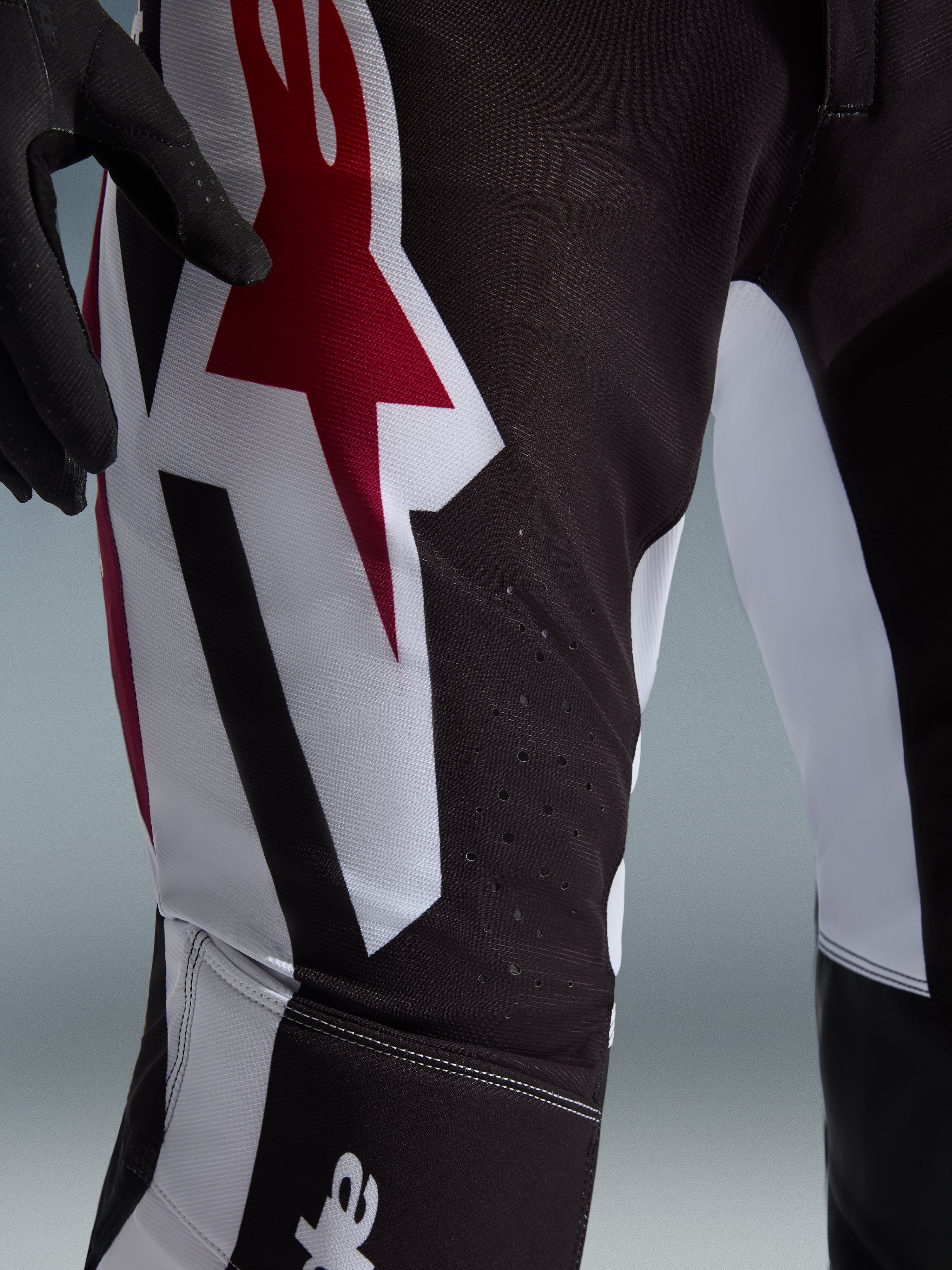 Alpinestars 2026 Supertech AFD Vista byxor, motocrossbyxor, svarta med röda och vita detaljer, närbild på lårområdet med en stor röd och vit stjärnlogotyp, laserskurna perforeringar för luftflöde och slitstarkt stretch-ripstopmaterial.