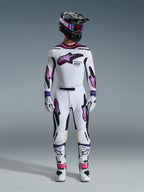 Motocross rider wearing a complete racing gear set, Alpinestars 2026 Supertech AFD Vista Pants and jersey in White Purple and Black, matching gloves, white and black boots, black helmet with purple goggles, sleek athletic fit for off-road performance