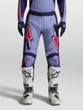 Alpinestars Racer Air Hunt motocrossbyxor i lila och violett med neonrosa detaljer, bärs med vita stövlar.