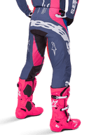 Alpinestars 2025 Techstar Dreem-byxor, motocrossbyxor, grå och starkt rosa, bärs med matchande rosa stövlar, med stor vit Alpinestars-logotyp på sätet och stjärnlogotyper på benen, slitstark atletisk tävlingspassform för terrängkörning