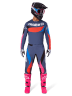 Alpinestars 2025 Techstar Dreem byxor, motocrossbyxor, grå multifärg med rosa och blå detaljer, bärs av en förare med matchande teknisk tröja, svart hjälm och klarrosa stövlar, komplett högpresterande racingutrustning för terrängkörning