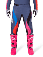 Alpinestars 2025 Techstar Dreem byxor, motocrossbyxor, grå multifärgade med rosa, blå och orangea detaljer, bärs med knallrosa motocross-stövlar och matchande tröja, atletisk racingpassform med laserskurna ventilationshål