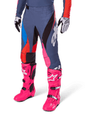 Alpinestars 2025 Techstar Dreem byxor, motocrossbyxor, mörkgrå med paneler i blått, rött och rosa, vit grafik, bärs med neonrosa stövlar och svartvita handskar, djärv design med hög synlighet