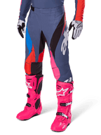 Alpinestars 2025 Techstar Dreem byxor, motocrossbyxor, mörkgrå med paneler i blått, rött och rosa, vit grafik, bärs med neonrosa stövlar och svartvita handskar, djärv design med hög synlighet