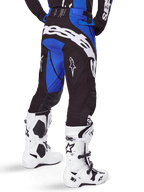 Alpinestars 2025 Techstar Dreem byxor, motocrossbyxor, svarta och blå, vy bakifrån med tydlig vit Alpinestars-logotyp på sätet, bärs med vita och svarta motocross-stövlar och matchande blå tröja, atletisk passform för terrängkörning