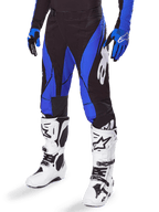 Alpinestars Techstar Dreem-byxor 2025, motocrossbyxor, svarta och blå, bärs med vita motocross-stövlar och blå handskar, med vit Alpinestars-logotyp på benet, slitstark konstruktion för terrängkörning