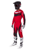 Motocross rider wearing complete racing gear featuring Alpinestars 2025 Techstar Dreem Pants in Bright Red and Black, matching red and black jersey with white logo, black helmet, and white and black boots, coordinated outfit for off-road racing