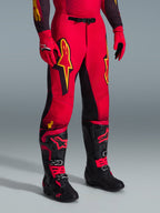 Alpinestars 2026 Supertech Scenz-byxor, motocrossbyxor, röd, svart och gul, med gula Alpinestars-logotyper och svarta paneler, bärs med matchande röd tröja, röda handskar och svarta motocross-stövlar.