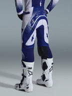 Alpinestars 2026 Supertech Scenz Pants, Motocross Pants, Light Gray and Dark Blue, rear view worn with matching jersey and white boots, featuring bold blue graphics with speckled accents, performance athletic fit for off-road racing.