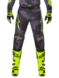 Alpinestars 2025 Racer Hollow Pants, motorcykelbyxor för motocross, mörkgrå med neongula detaljer, gula stjärnlogotyper, kombinerad med neongula stövlar och svarta handskar, skyddande sportdesign